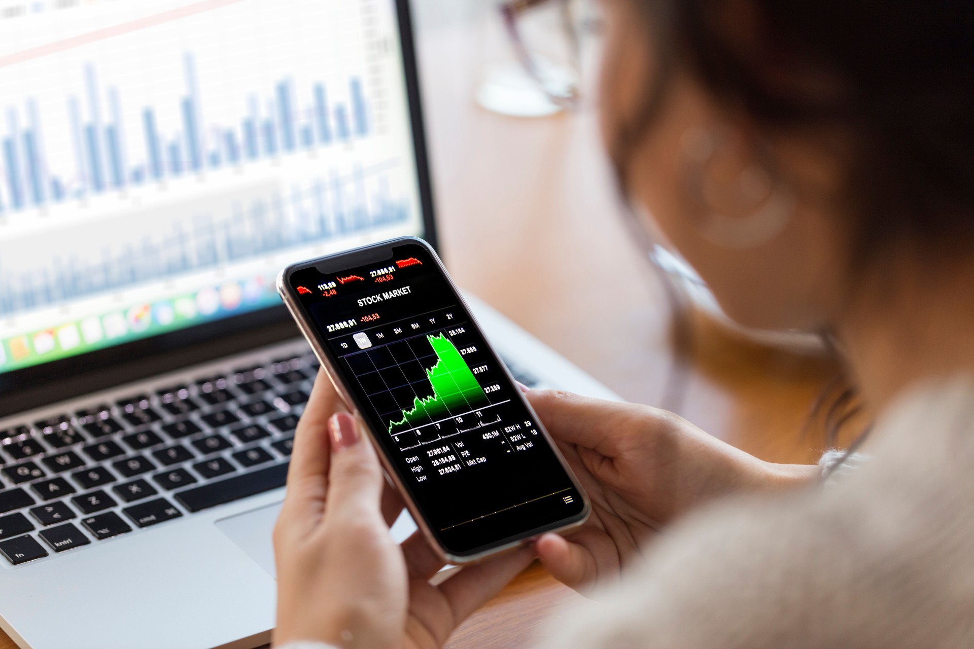 Young finance expert  analyzing financial charts on smart phone